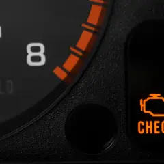 Pomarańczowa kontrolka silnika "CHECK ENGINE" na desce rozdzielczej samochodu.