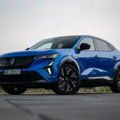 Błękitny Renault Rafale z czarnymi felgami stoi na drewnianym tarasie.