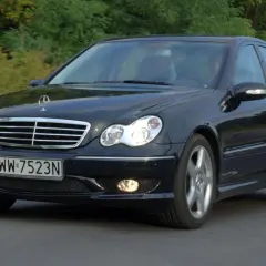 Czarny Mercedes-Benz w203 z tablicą rejestracyjną WW 7523N jedzie po drodze wśród zieleni.