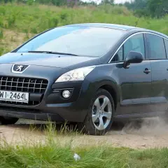 Ciemnoszary Peugeot 3008 1.6 HDI na drodze gruntowej, wzbijający tumany kurzu.