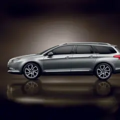 Srebrny Citroen C5 X7 kombi z przyciemnianymi szybami i eleganckimi felgami, odbijający się od błyszczącej powierzchni.