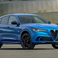Błękitne Alfa Romeo Stelvio Quadrifoglio z czarnymi felgami i czerwonymi zaciskami hamulcowymi, gotowe do dynamicznej jazdy.