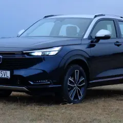 Ciemnoniebieski Honda HR-V na tle suchej trawy i jeziora.