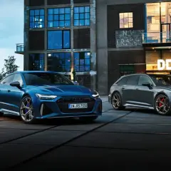 Dwa Audi RS6: niebieski sedan i szary Avant, zaparkowane przed budynkiem z napisem "DOCKS".