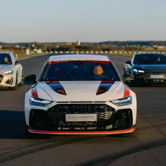Trzy samochody Audi RS 8 na torze wyścigowym. Biały RS 8 z czerwonymi akcentami na pierwszym planie, za nim biały i czarny RS 8.