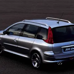 Srebrny Peugeot 206 SW z relingami dachowymi i podwójnym wydechem, zaparkowany na ciemnym asfalcie.