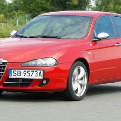 Czerwone Alfa Romeo 147 1.9 JTD w ruchu, z widocznymi felgami w ruchu.