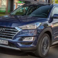 Ciemnoniebieski Hyundai Tucson 2025 w ruchu miejskim, z widocznym grillem i reflektorami.