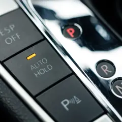 Przyciski ESP OFF, AUTO HOLD i P w samochodzie. Dźwignia zmiany biegów z literami P, R, N, D i przyciskiem "+", sugerująca tryb tiptronic.