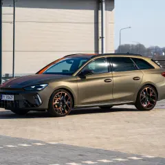 Złoty Cupra Leon Kombi z miedzianymi akcentami na felgach i dachu, zaparkowany na zewnątrz.