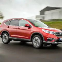 Czerwony Honda CR-V 4. generacji pędzi po torze wyścigowym, ukazując swoją dynamiczną sylwetkę.