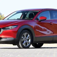 Czerwona Mazda CX-30 z polskimi tablicami rejestracyjnymi stoi na zewnątrz.