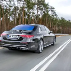 Czarny Mercedes S400d 4Matic z tablicą WW 800SL jedzie po drodze wśród drzew.