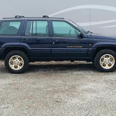 Granatowy Jeep Grand Cherokee ZJ z lat 90. na złotych felgach, gotowy na przygodę.