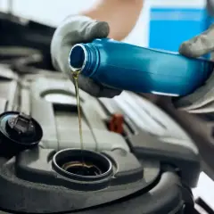 Ręce w rękawiczkach wlewają olej silnikowy 5W30 do silnika. Czy to Motul czy Castrol?