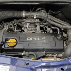 Silnik Opla Meriva A z widocznym napisem OPEL. Widać przewody, rury i żółty korek wlewu oleju.