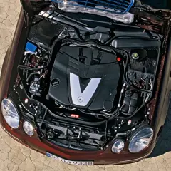 Silnik V6 om642 Mercedesa E-klasy, z otwartą maską, na tle spękanej ziemi.