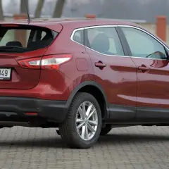 Czerwony Nissan Qashqai 1.6 benzyna z czeskimi tablicami rejestracyjnymi stoi na utwardzonym podjeździe.