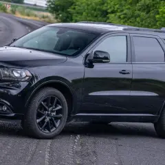Czarny Dodge Durango 5.7 Hemi na krętej drodze, otoczony zielenią. Potężny SUV gotowy na każdą przygodę.