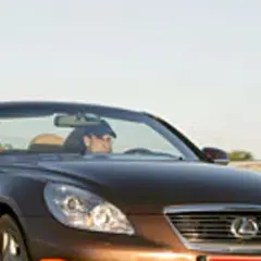 Brązowy kabriolet Lexus SC430 z otwartym dachem, kierowca w czapce, jazda w słoneczny dzień.