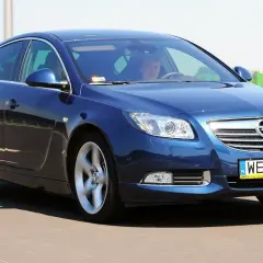 Niebieski Opel Insignia 2.0 Turbo pędzi po drodze, kierowca skupiony na trasie.