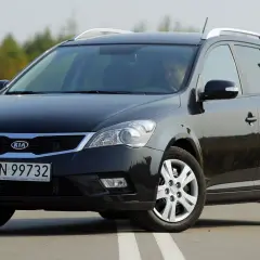 Czarny Kia Ceed 1. kombi na drodze, z kierowcą za kierownicą.