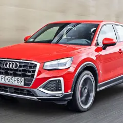 Czerwone Audi Q2 pędzi po drodze, błyszcząc w słońcu.