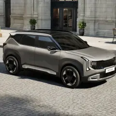Nowy model Kia, szary SUV, parkuje na brukowanej ulicy przed eleganckim budynkiem.
