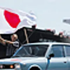 Jasnoniebieski Datsun 100A z flagą Japonii na tle statku.