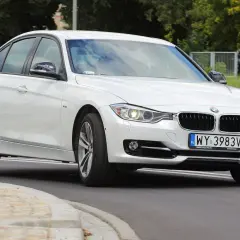 Białe BMW 318i z polskimi tablicami rejestracyjnymi WY 3983V jedzie po drodze.