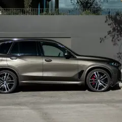 Elegancki mężczyzna w garniturze obok lśniącego BMW G05.