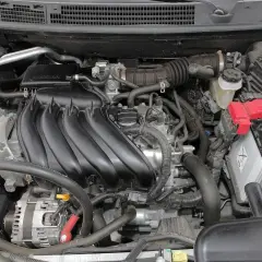 Silnik Nissan Qashqai J10, z widocznym kolektorem dolotowym, akumulatorem i alternatorem.