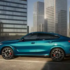 Błękitne x6 BMW lśni na tle nowoczesnych wieżowców.