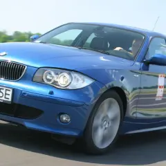 Niebieskie BMW e81 z polskimi tablicami WI 4875E na zakręcie toru wyścigowego.