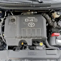 Silnik D-4D w Toyocie Corolla E12. Widoczny jest plastikowy kolektor dolotowy, akumulator i inne elementy komory silnika.