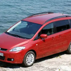 Czerwona Mazda 5 2.0 benzyna zaparkowana przy wodzie.