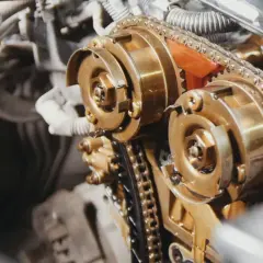 Zbliżenie na mechanizm rozrządu silnika diesla z widocznym łańcuchem i kołami zębatymi.