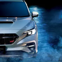 Srebrny Subaru Levorg STI Sport z włączonymi światłami, otoczony niebieską mgłą, gotowy do jazdy.