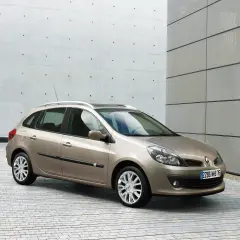 Beżowe Renault Clio 3 1.2 benzyna na tle nowoczesnej architektury.