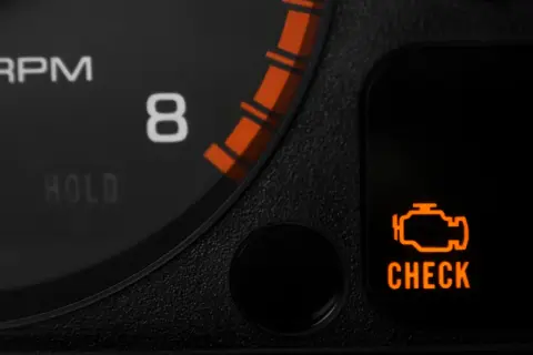 Pomarańczowa kontrolka silnika "CHECK ENGINE" na desce rozdzielczej samochodu.