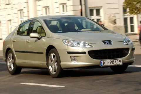 Złoty Peugeot 407 2.0 HDI jedzie ulicą.