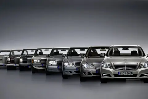 Rząd klasycznych i nowoczesnych Mercedesów klasy E, od starszych modeli po najnowsze, prezentuje ewolucję designu.