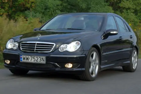 Czarny Mercedes-Benz w203 z tablicą rejestracyjną WW 7523N jedzie po drodze wśród zieleni.
