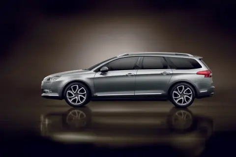 Srebrny Citroen C5 X7 kombi z przyciemnianymi szybami i eleganckimi felgami, odbijający się od błyszczącej powierzchni.