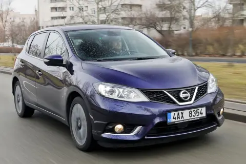 Fioletowy Nissan Pulsar w ruchu ulicznym. Wiele osób szuka nissan pulsar opinie przed zakupem.
