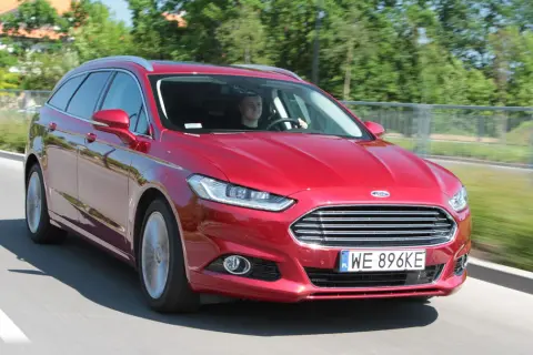 Czerwony Ford Mondeo MK4 kombi w ruchu drogowym. Kierowca uśmiecha się, a opinie o tym modelu są zazwyczaj pozytywne.