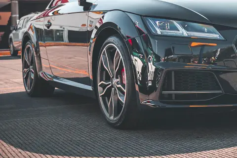 Błyszczące, czarne auto sportowe z felgami i widocznym rantem ochronnym opony.