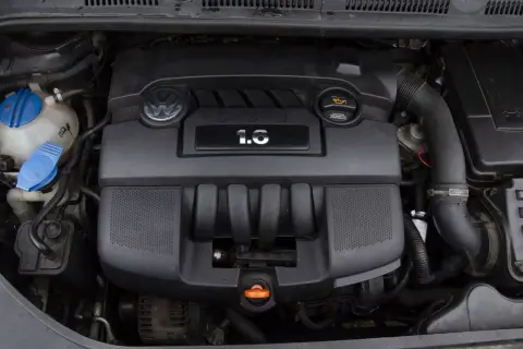 Silnik Volkswagena z oznaczeniem 1.6 MPI. Widoczny jest czarny plastikowy kolektor, logo VW i zbiornik płynu chłodniczego.