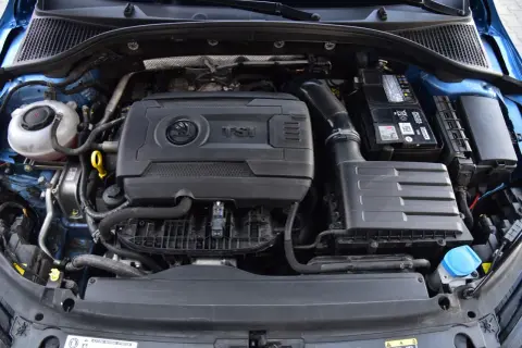 Silnik 1.8 TFSI w samochodzie Skoda. Widoczny jest blok silnika, akumulator, obudowa filtra powietrza i zbiornik płynu chłodniczego.