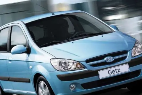 Błękitny Hyundai Getz w ruchu miejskim, z rozmytym tłem sugerującym prędkość.
